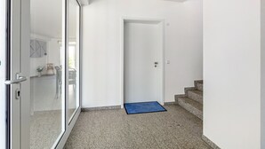 Ein Flur mit Glastür, weißer Tür und einer blauen Matte, die zu einer Treppe führt.
