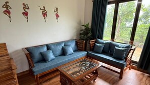 A living room with a blue sofa, a wooden coffee table, and wall art. - Misty Falls (Karjat)
