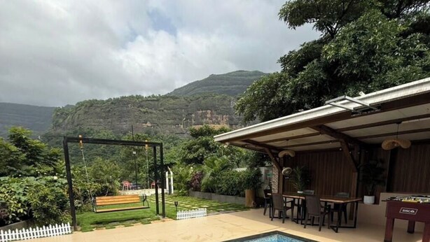 A swimming pool with a view of a mountainous landscape. - Misty Falls (Karjat)