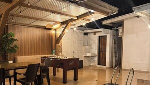 A pool area with a table and chairs, a ladder, and a door leading to a bathroom. - Misty Falls (Karjat)