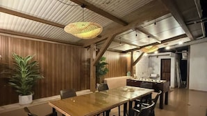 A dining area with a wooden table and chairs, a hanging light fixture, and wooden paneling on the walls. - Misty Falls (Karjat)