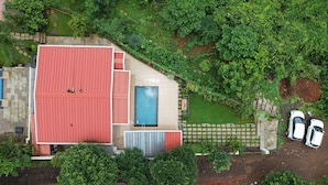 A house with a red roof, a swimming pool, and two cars parked outside. - Misty Falls (Karjat)