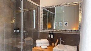 A modern bathroom with a glass-enclosed shower, a large mirror, and a wooden vanity with a sink. - Hotel Adagio (Barcelona)