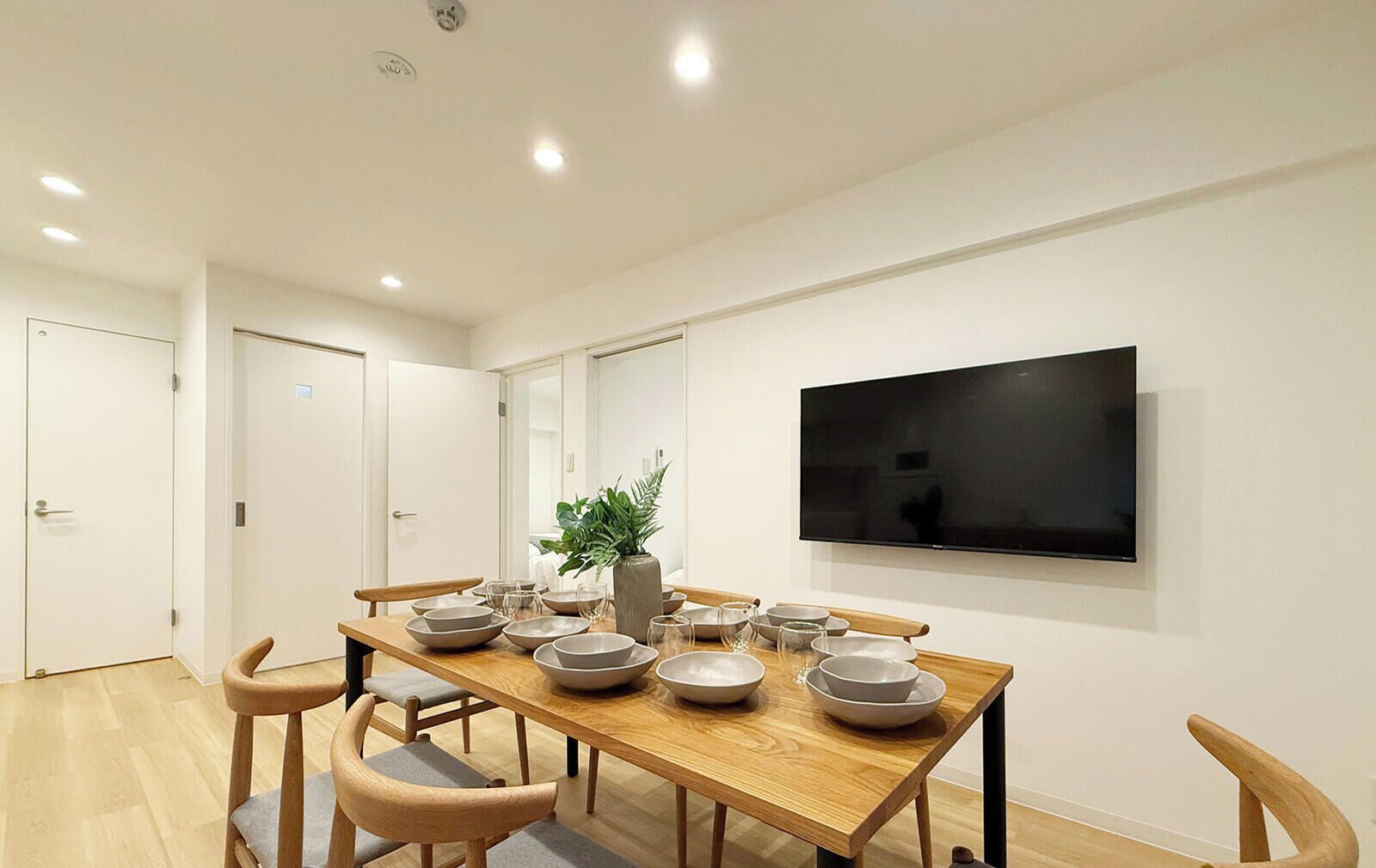 A dining area with a wooden table, chairs, and a TV mounted on the wall.