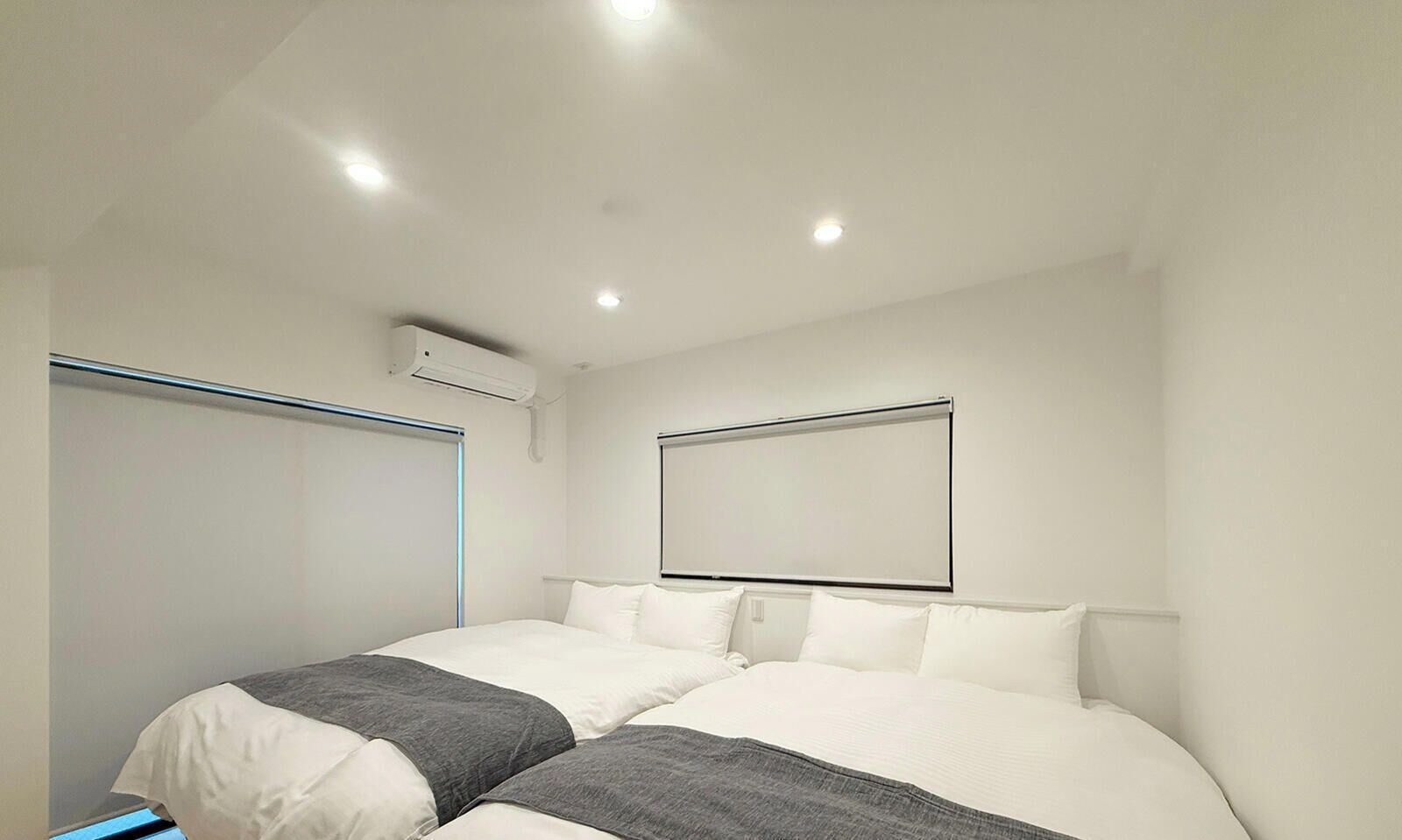Une chambre d’hôtel moderne avec deux lits, une grande fenêtre et un appareil de climatisation.