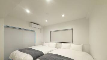 Une chambre d’hôtel moderne avec deux lits, une grande fenêtre et un appareil de climatisation.