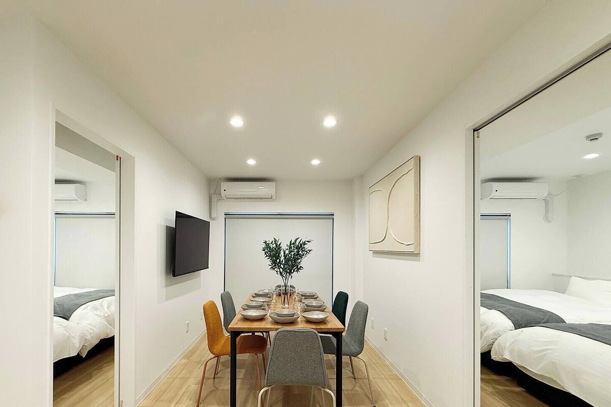 Ein kleines Hotelzimmer mit Essbereich, Fernseher, Spiegel und einer Pflanze.