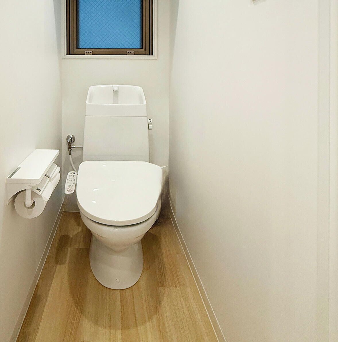 A small, modern bathroom with a toilet, a bidet, and a control panel.