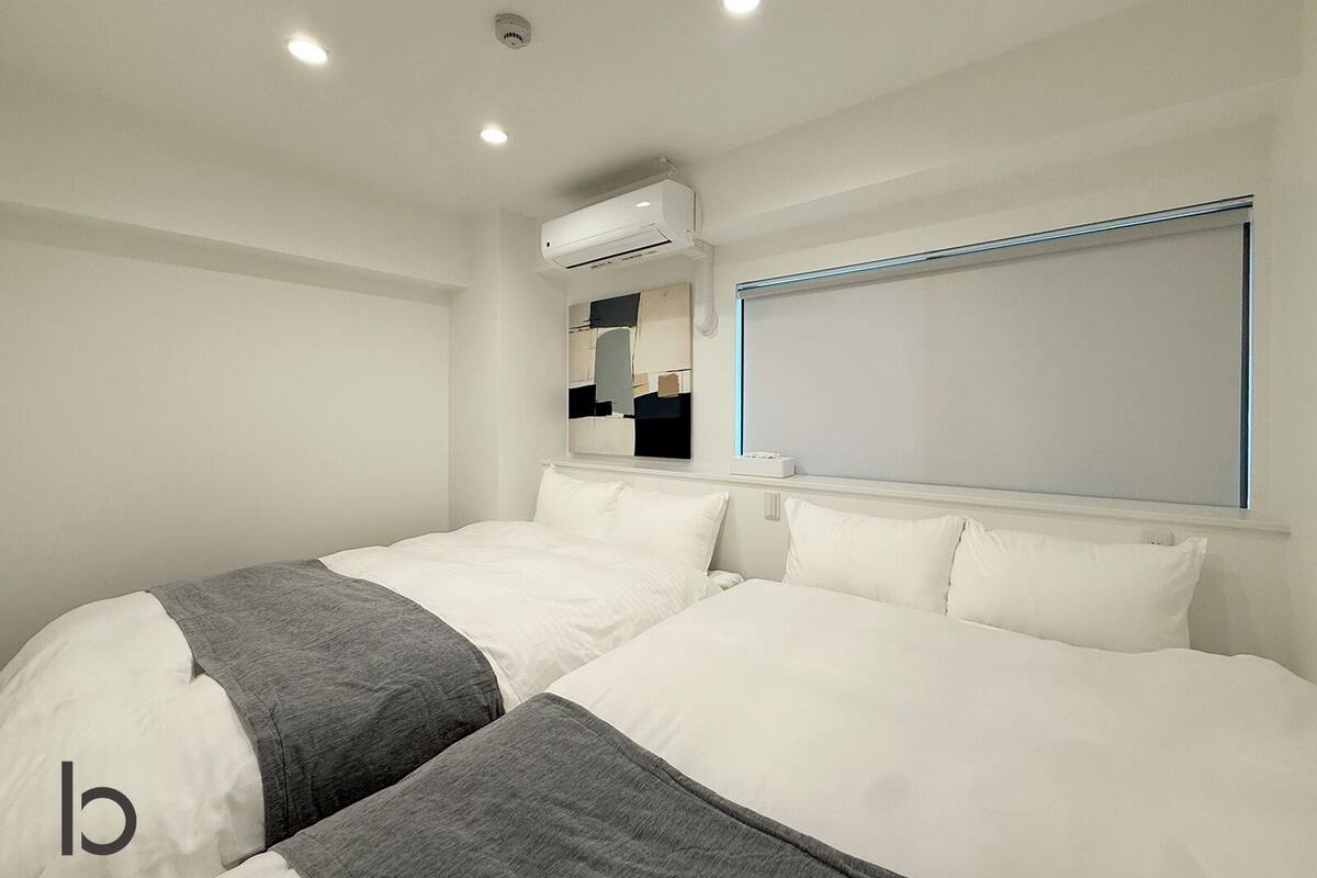 Ein modernes Hotelzimmer mit einem großen Bett, einer Klimaanlage, einem Fenster mit Jalousien und einem an der Wand befestigten Spiegel.