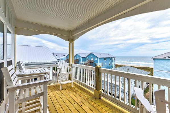 A wooden deck with a railing, a table, and two chairs. - Big Blue - Second Row Home with Ocean Views! (Carolina Beach)