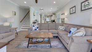Ein Wohnzimmer mit Sofa, Couchtisch und einer Treppe, die zur Küche führt.