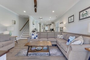 Ein Wohnzimmer mit Sofa, Couchtisch und einer Treppe, die zur Küche führt.