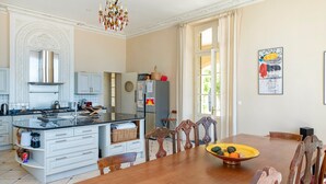 Una cocina con isla central, mesa de comedor de madera, sillas y una lámpara de araña.