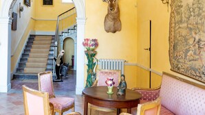 Una imponente escalera, una cabeza de animal montada como trofeo, una mesa con un jarrón y un cuadro en la pared.