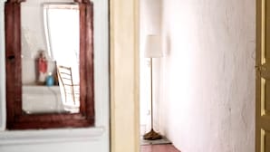 Un pasillo con un espejo, una lámpara y una puerta.
