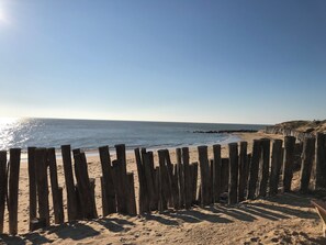 A beach with a wooden fence, sandy beach, and clear blue sky. - Charming villa 'Le Refuge' heated pool 300m from the beach in a quiet location (La Tranche-sur-Mer)