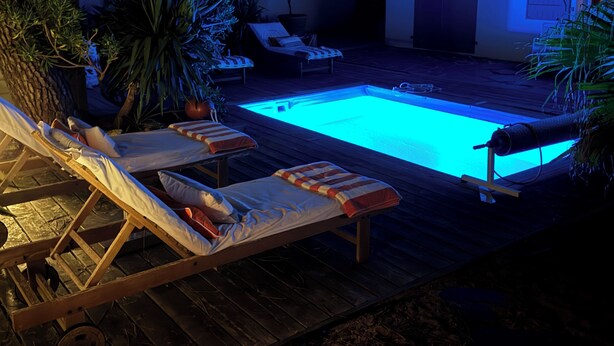 Piscina com espreguiçadeiras e plantas em vasos.