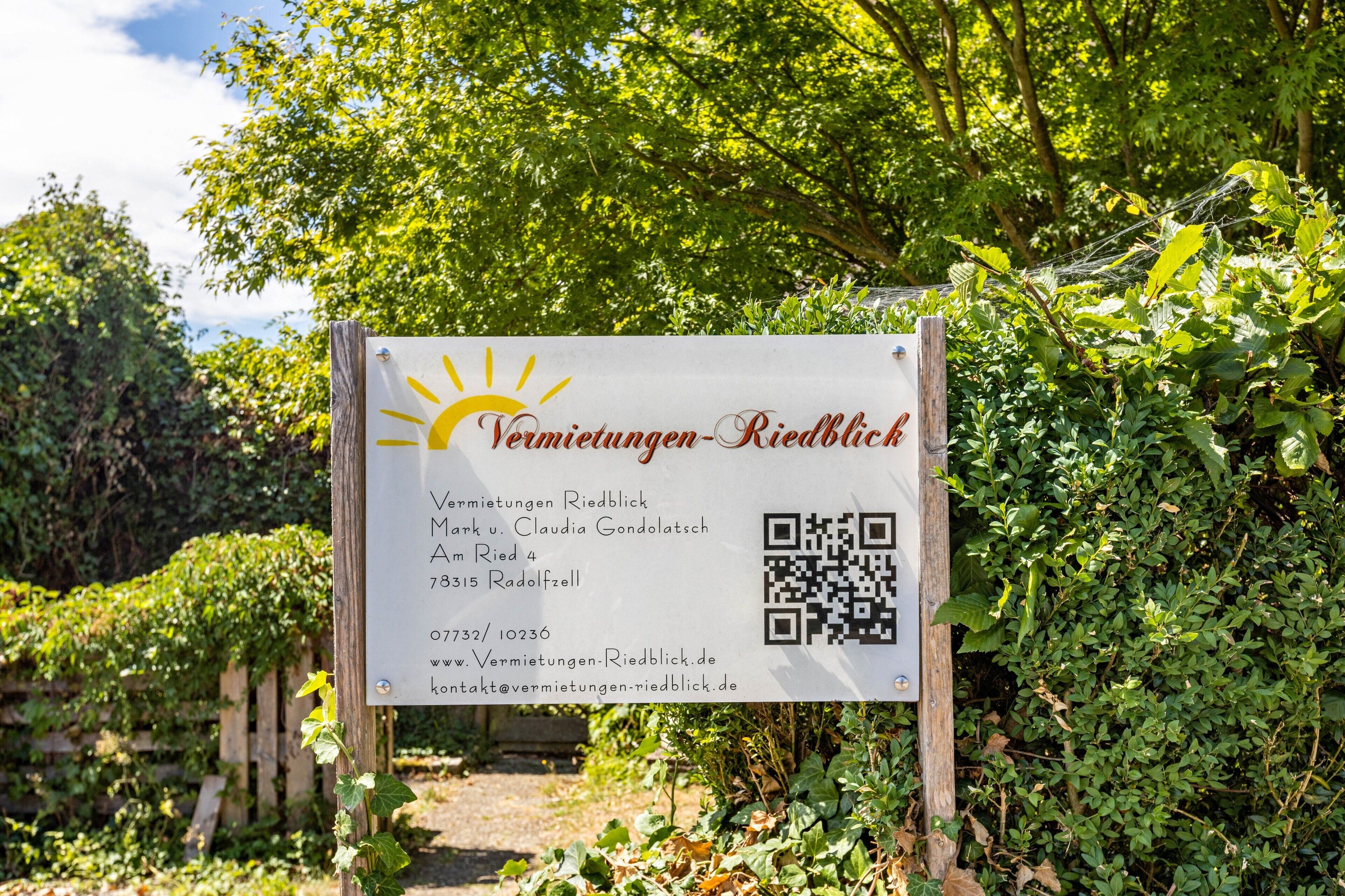 A sign with contact information for Vermietungen-Riedblick, including a QR code, website, and email address.