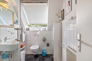 Een moderne badkamer met dakraam, toilet, wastafel en handdoekhouder.