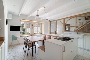 A modern kitchen with a large island, wooden dining table, and a view of the outside. - Holiday Home “La Maison Du Cap” with Private Terrace, Wi-Fi, and Air Conditioning (Plévenon)