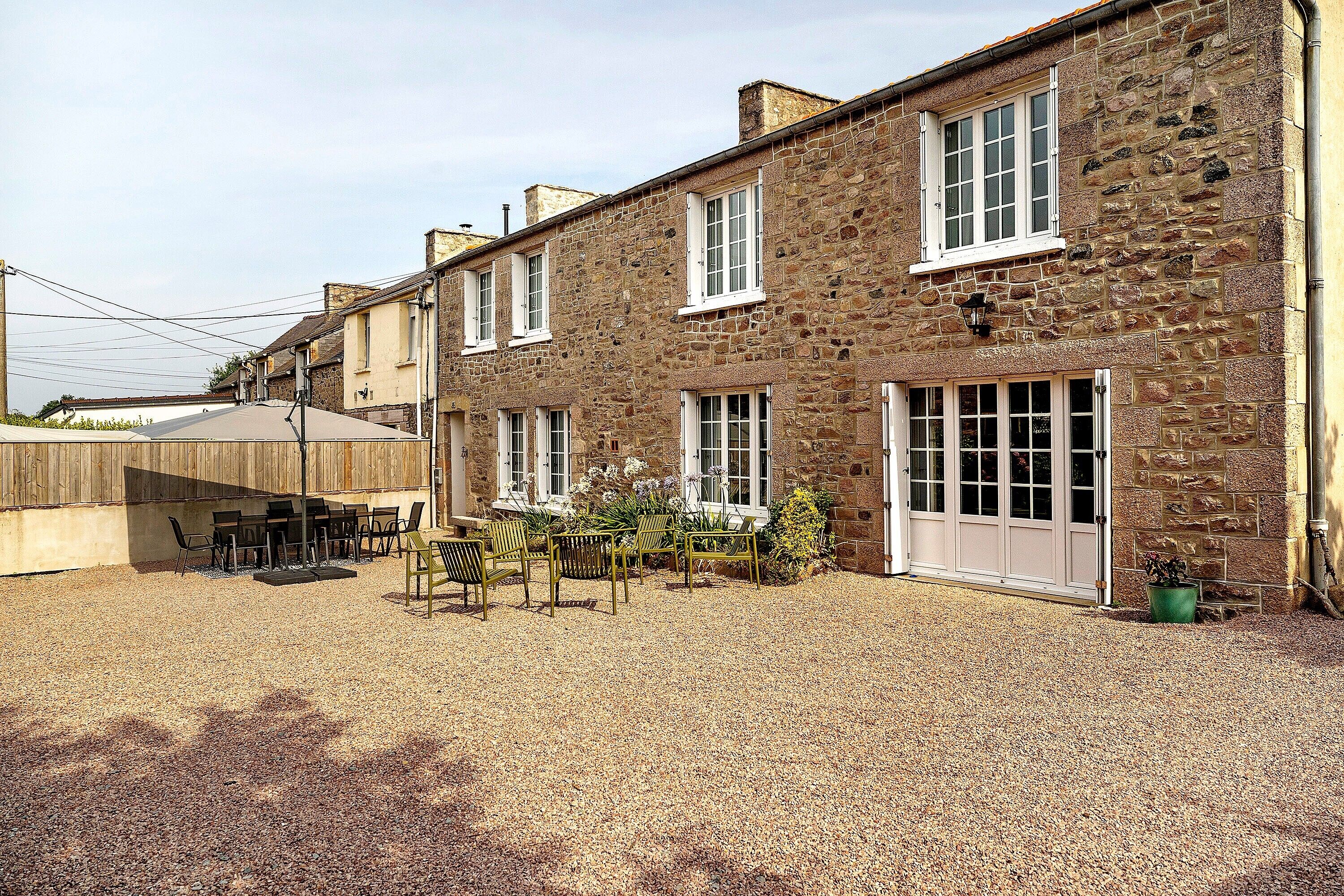 A stone building with a gravel patio and outdoor seating.
