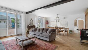 Ein geräumiges Wohnzimmer mit einem grauen Sofa, einem Holztisch und einem roten Teppich mit Muster.