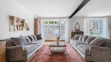 A spacious living room with two grey sofas, a coffee table, and a patterned rug.