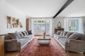 A spacious living room with two grey sofas, a coffee table, and a patterned rug. - Holiday Home “La Maison Du Cap” with Private Terrace, Wi-Fi, and Air Conditioning (Plévenon)
