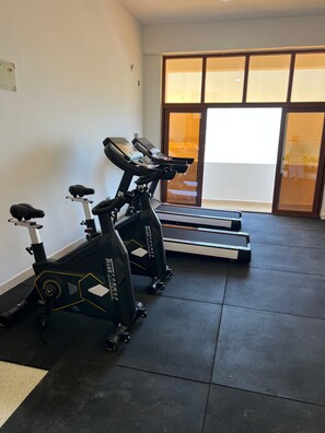 A gym with stationary bikes and treadmills, a tiled floor, and a large window with a view. - Luxury Living in Nyali — Wake up to breathtaking ocean view (Mombasa)