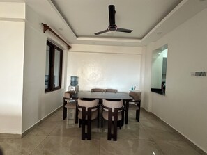A dining area with a round table, six chairs, a ceiling fan, a water dispenser, and a small sink. - Luxury Living in Nyali — Wake up to breathtaking ocean view (Mombasa)