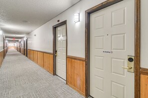 Ein Hotelkorridor mit Holzwandverkleidung, weißen Türen und Teppichboden.