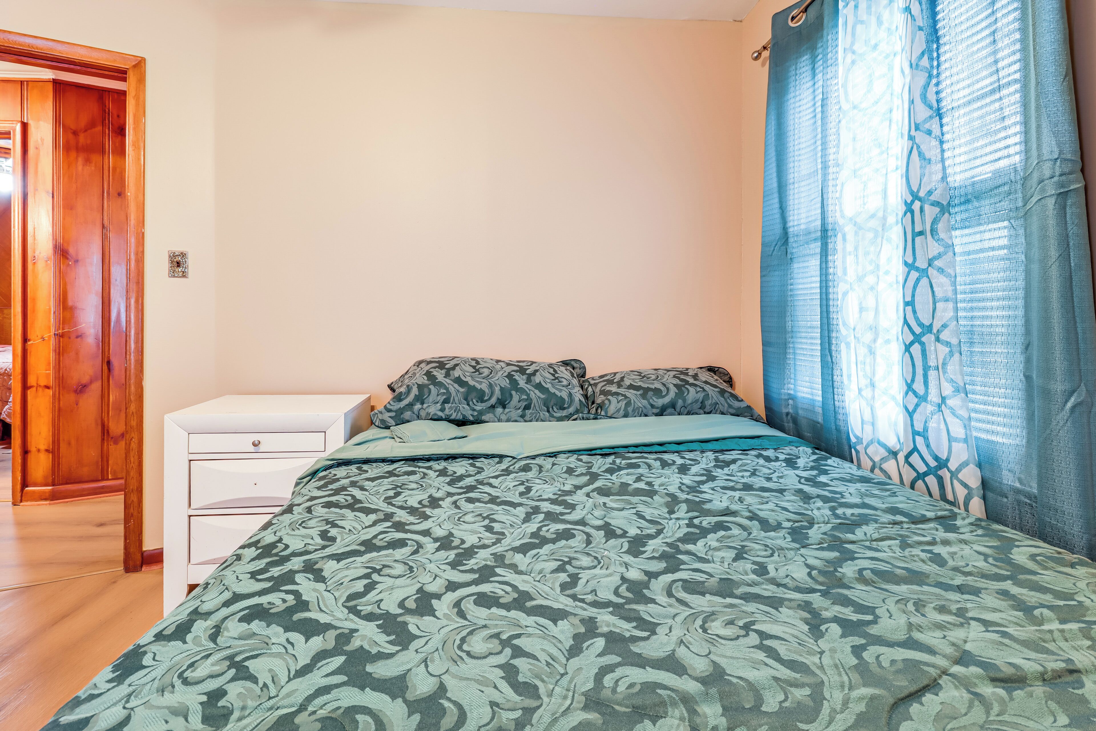 A bedroom with a bed, a nightstand, and a wooden door.