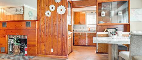 A wooden interior with a fireplace, a dining area, and a kitchen with wooden cabinets.