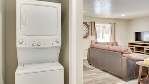A laundry area with a washing machine and a living room with a sofa and a television.