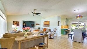 A spacious living area with a sofa, coffee table, and a dining area with chairs. - Luxe Detached Home in Age 55 Plus Active Community (Sun City West)