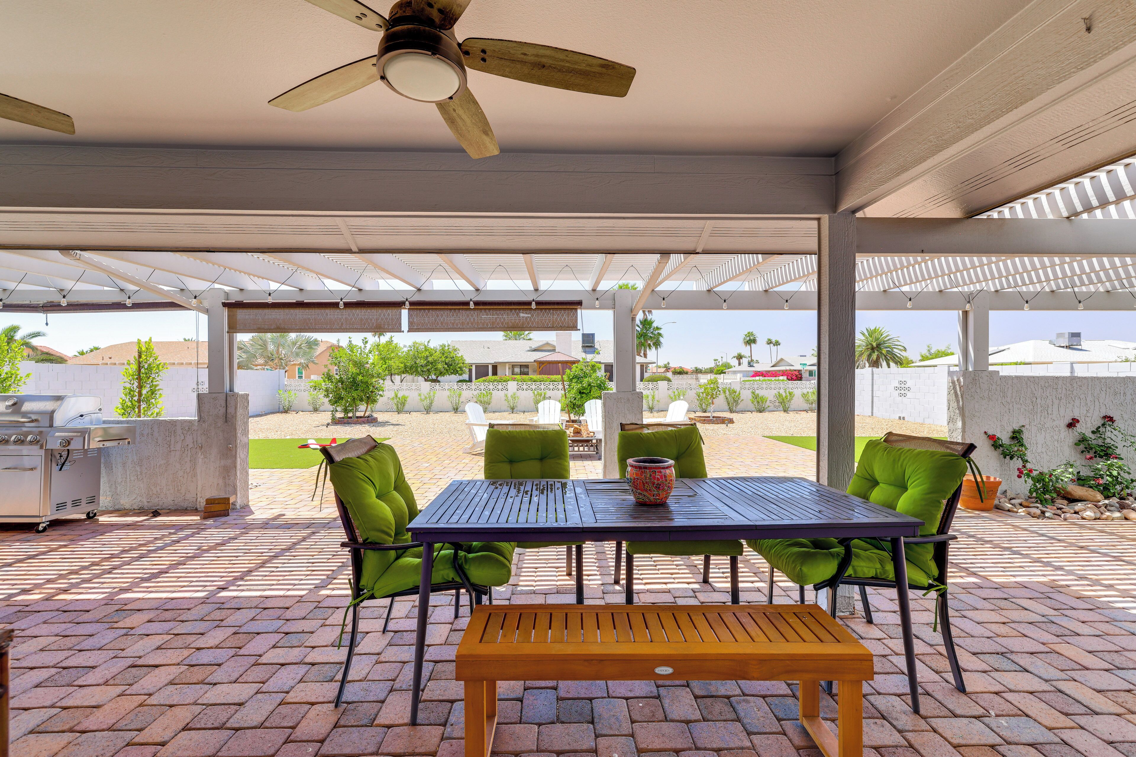 Eine Terrasse im Freien mit Tisch, Stühlen, Deckenventilator und Grill.