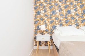 A bedroom with a floral wallpaper, a bedside table with a lamp, and a bed with white bedding. - Flower House 7 New, quiet, modern (Granada)