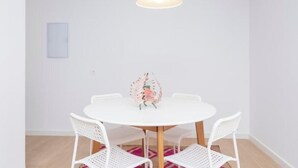 Un tavolo rotondo bianco con quattro sedie bianche, un lampadario a sospensione e un piccolo oggetto decorativo sul tavolo.