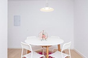 A round white table with four white chairs, a hanging light fixture, and a small decorative item on the table. - Flower House 7 New, quiet, modern (Granada)