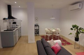 A compact living space with a kitchenette, dining area, and a sofa with a red pillow. - Flower House 7 New, quiet, modern (Granada)