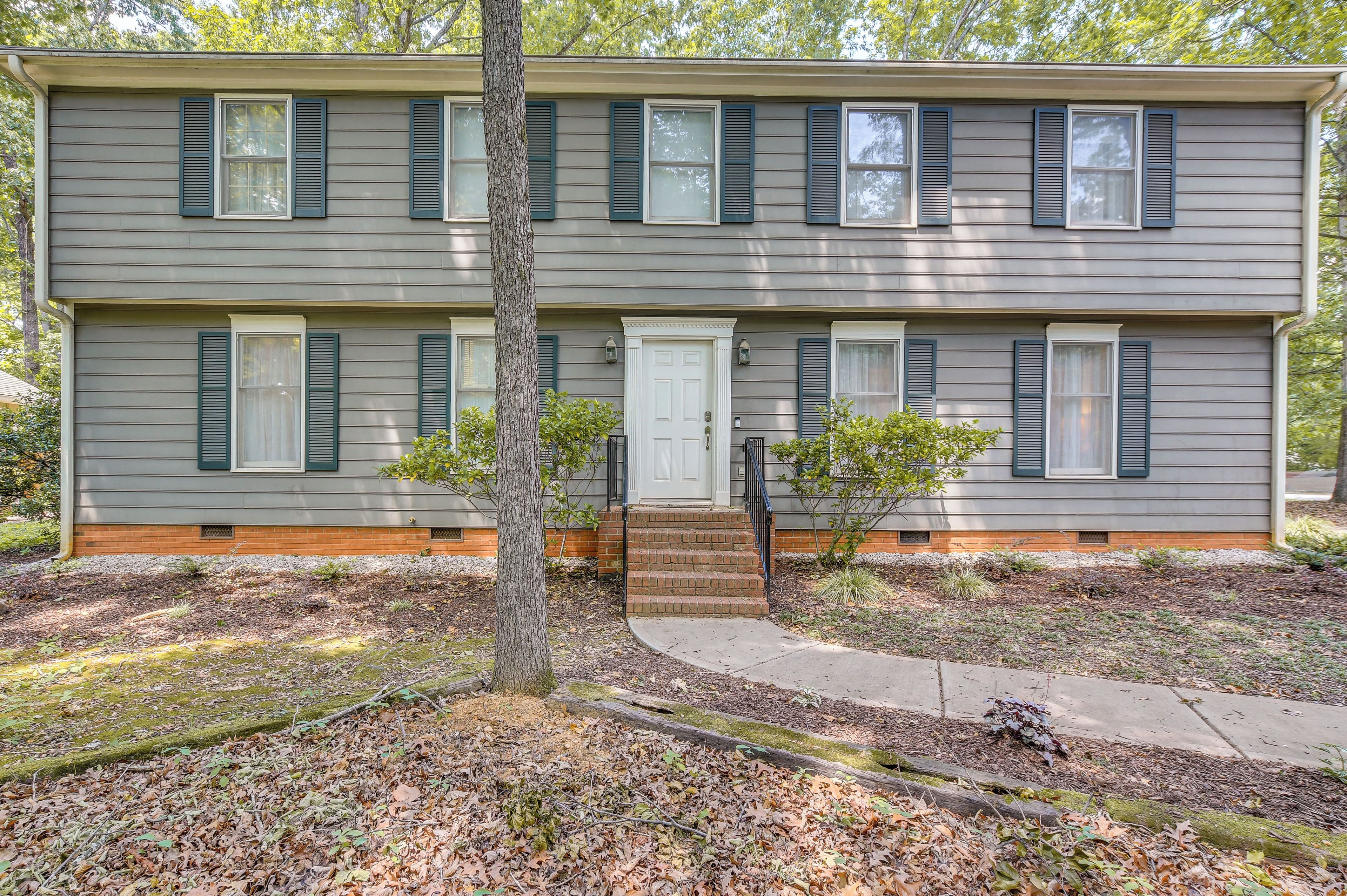 A two-story building with a front door, a small front yard, and a tree.