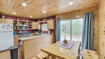 A wooden cabin kitchen with a central island, wooden cabinets, a microwave, and a sink.