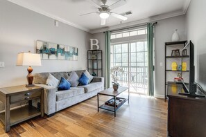 A living room with a sofa, coffee table, TV stand, and a ceiling fan. - Disney Magic & Tuscana Resort Fun! Family Condo (Davenport)