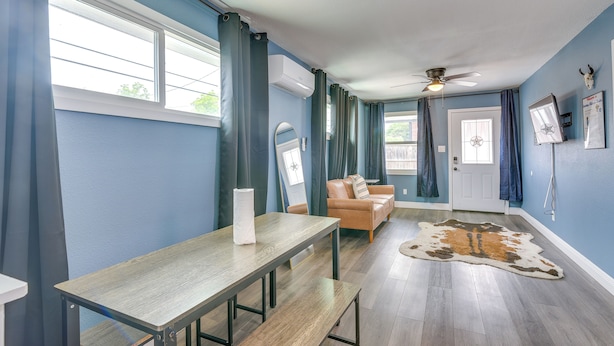 Una habitación con una mesa de madera, un sofá de cuero, un ventilador de techo y un tapete de piel de vaca.