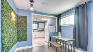 Una cocina moderna con una pared verde, un área de comedor con un banco y vistas al espacio de estar contiguo.
