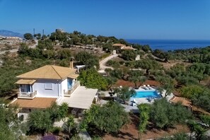 Eine Villa mit Swimmingpool, umgeben von Bäumen und Blick aufs Meer.