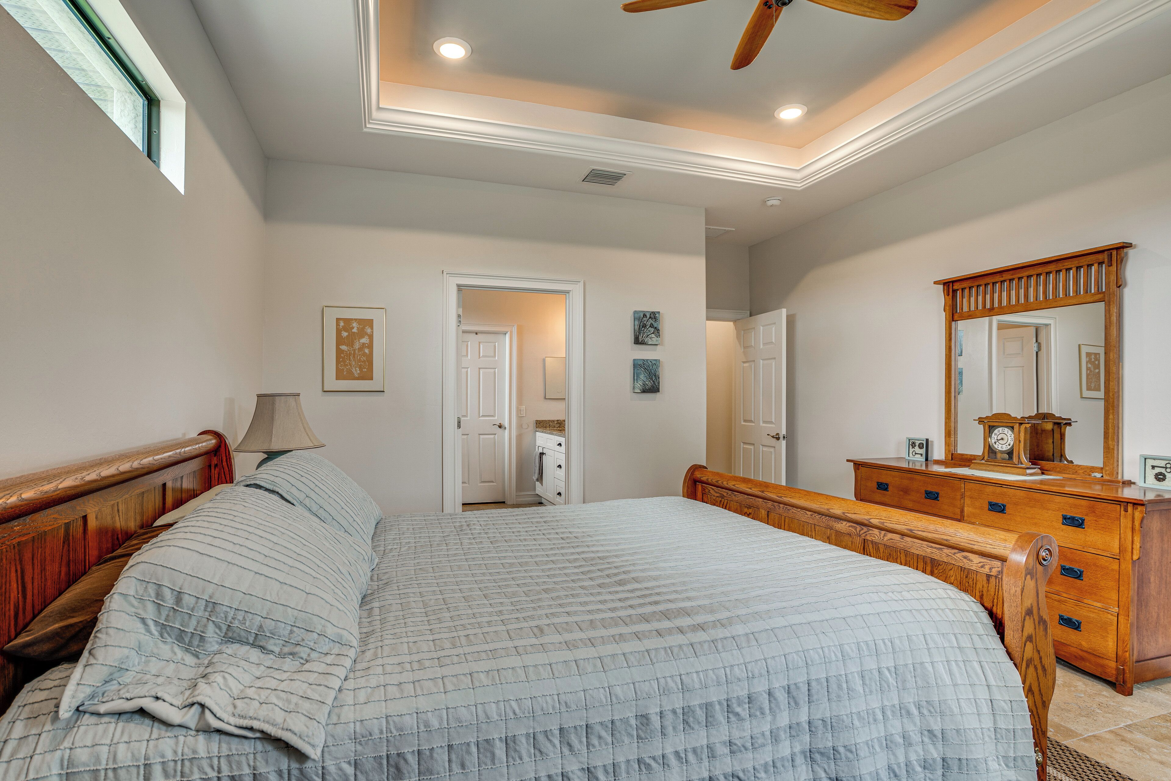 A bedroom with a bed, dresser, mirror, and a ceiling fan.