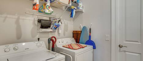 A laundry area with two washing machines, shelves with cleaning supplies, and a door with a handle.