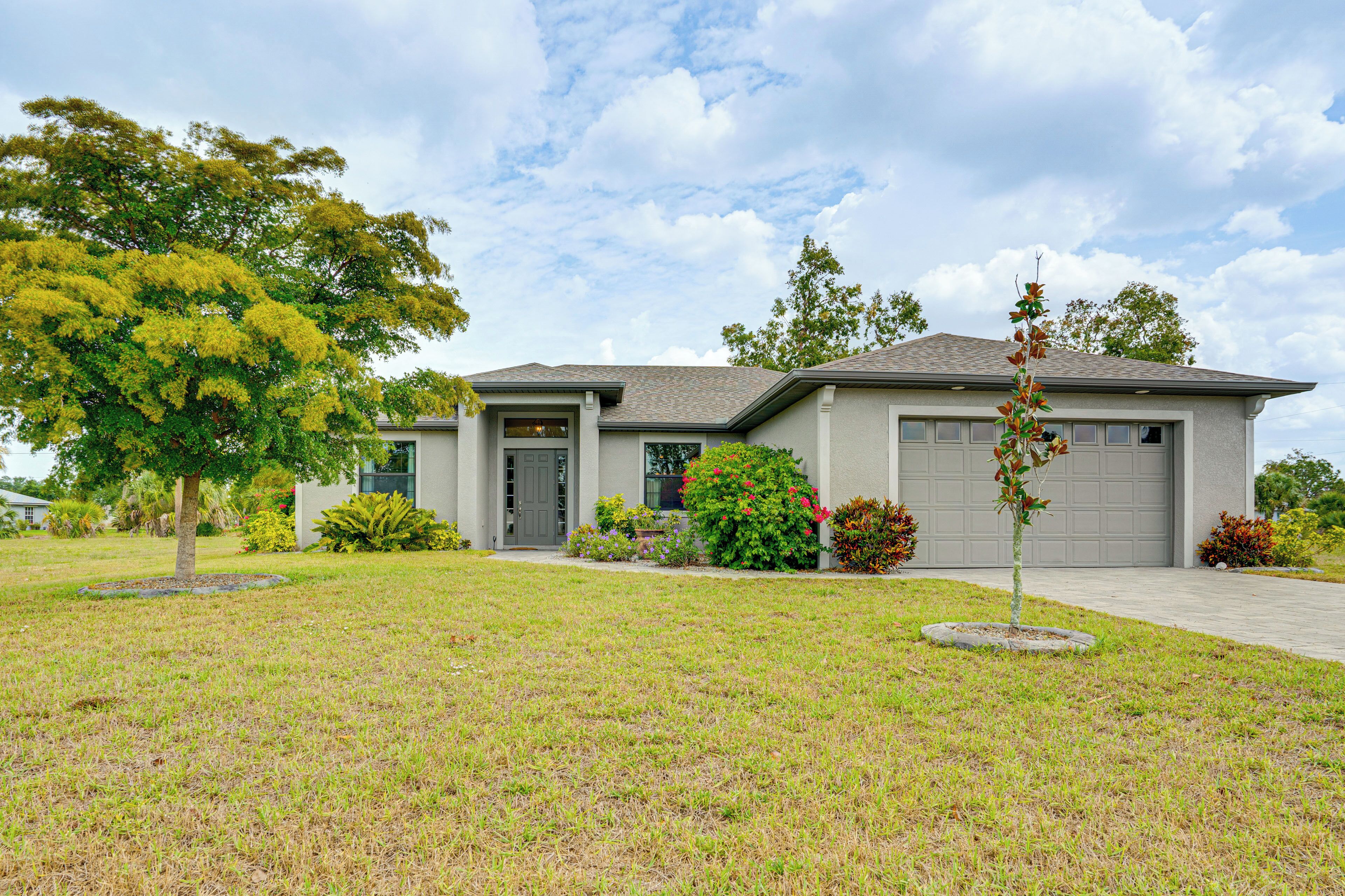 A two-story house with a garage, surrounded by a well-maintained lawn and various shrubs.