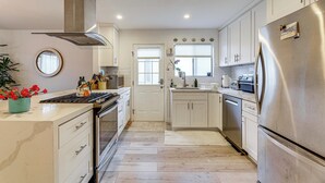 Una cocina moderna con electrodomésticos de acero inoxidable, armarios blancos y una isla central con un fregadero.